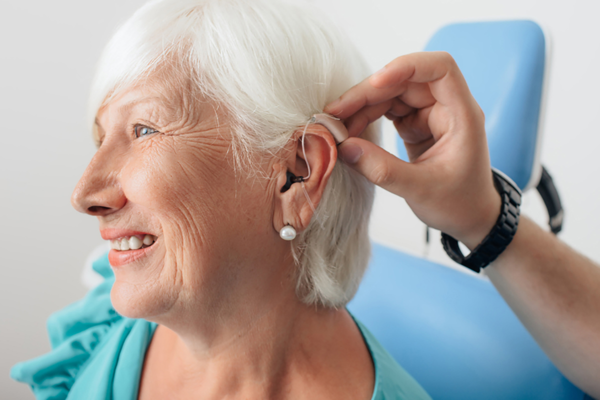 Medicare Insurance - Elderly woman getting fitted with hearing aids